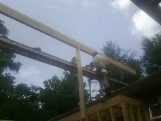 Carpenter setting a ridge beam over a new addition frame — Ice Dam Removal by Roofing Brothers in Fort Branch