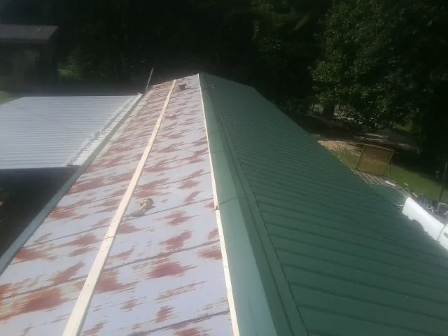 Old rusted panels beside newly installed green metal roofing — Wind Damage Roof Repair by Roofing Brothers in Fort Branch