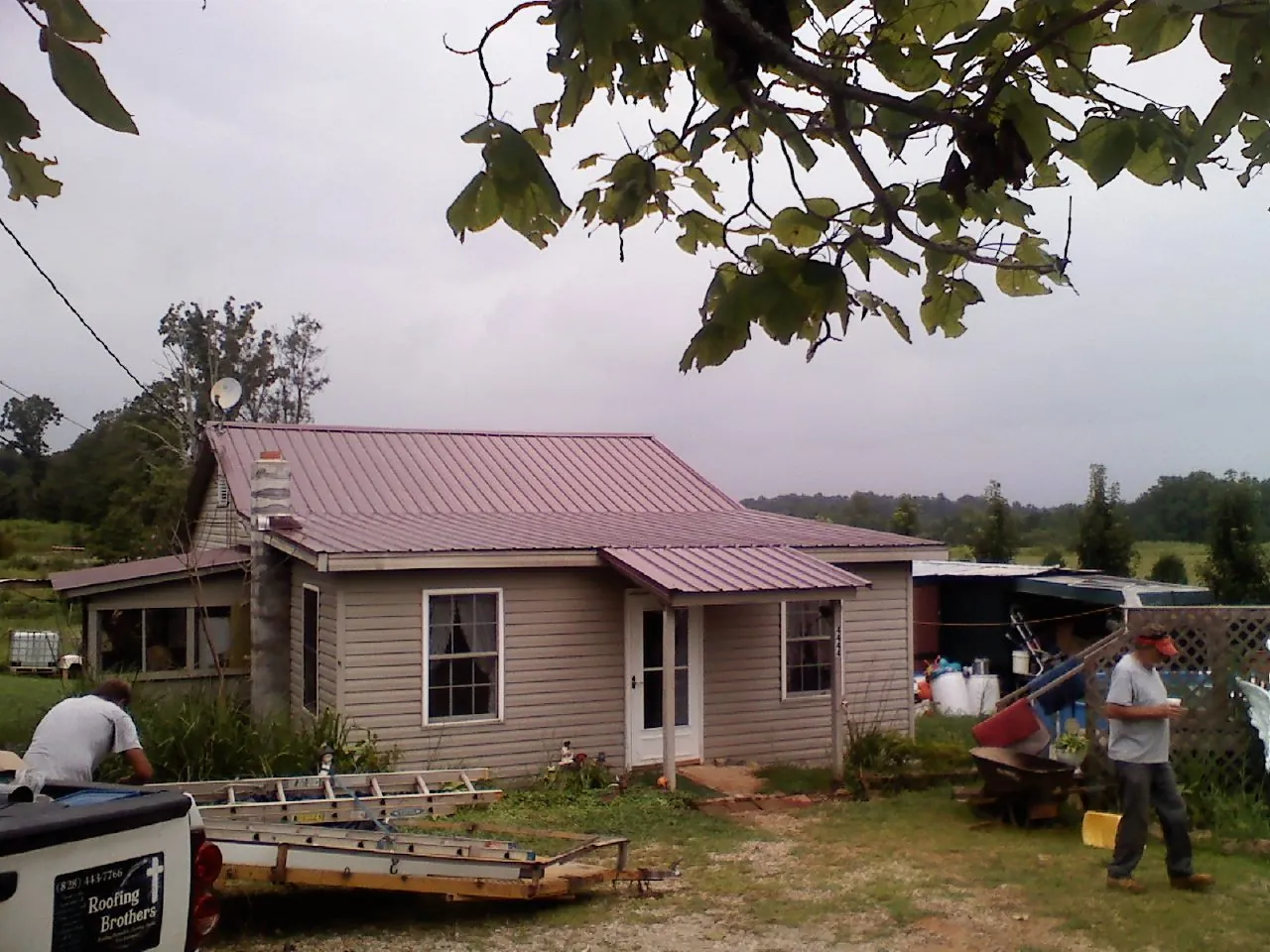 Crew finishing a mauve metal roof on a small farmhouse in Fort Branch
