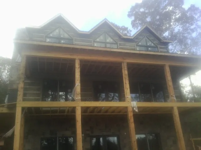 Dormers and porch framing on a large log home under construction — Roof Coating work by our crew in Fort Branch