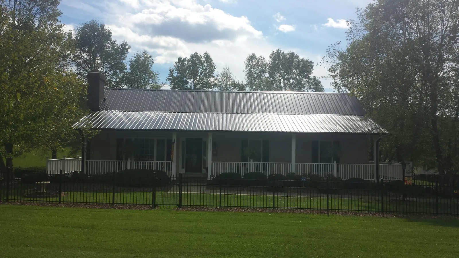 Gray metal roof on a brick ranch with a full width front porch — Gutter Guard Installation work by our crew in Fort Branch