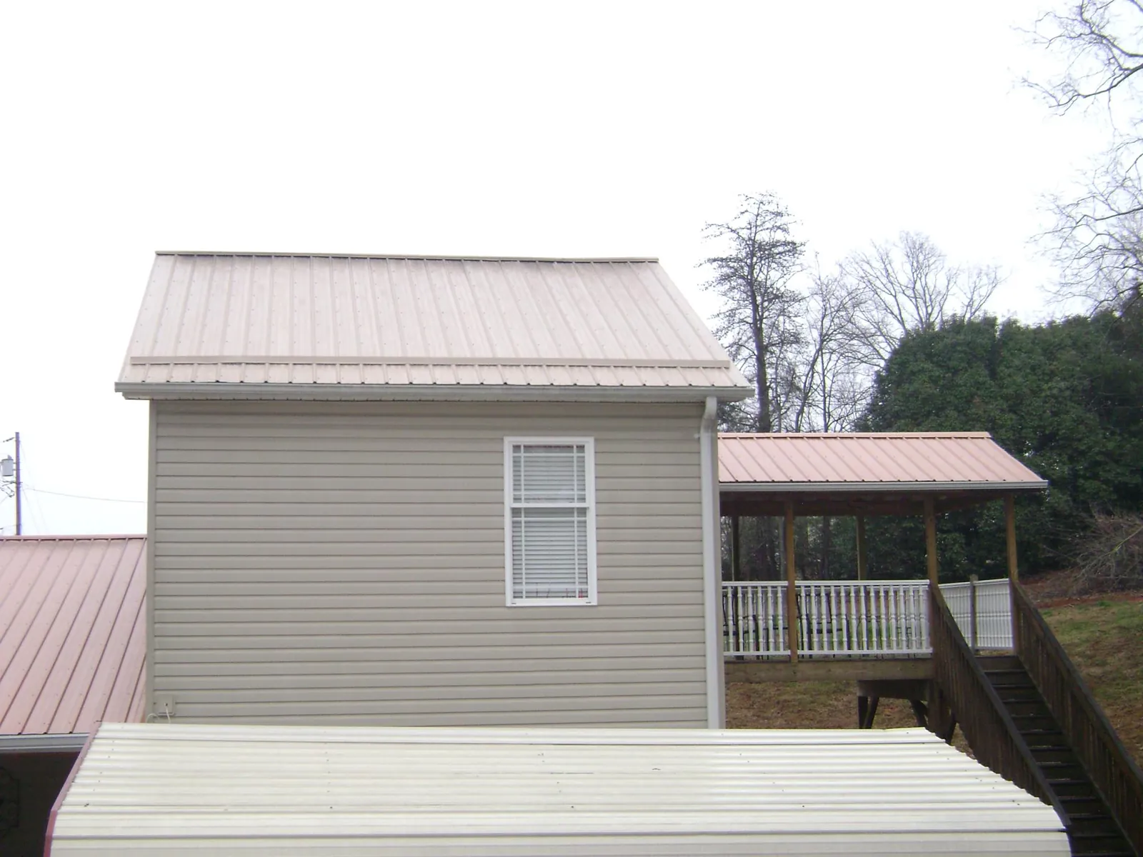 Tan metal roofs on a two story addition and attached porch, from a Roof Replacement job in Fort Branch