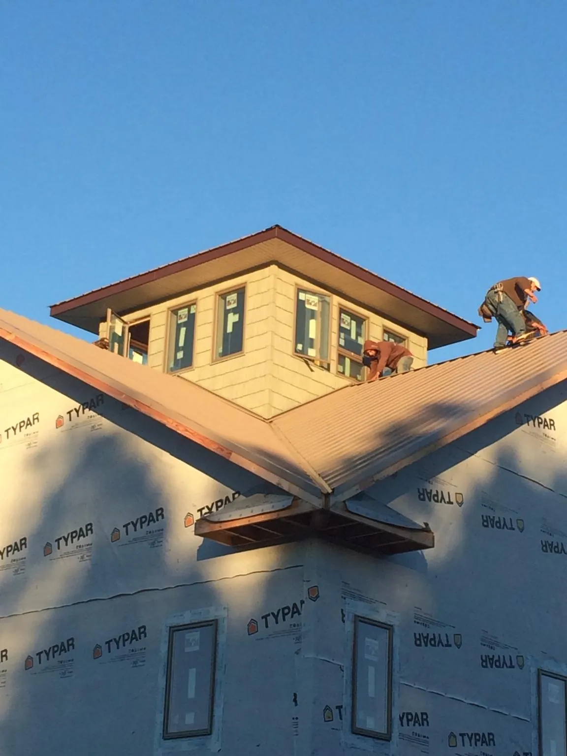 Roofers working around a rooftop cupola on a new metal roof at sunset — Roof Waterproofing in Fort Branch by Roofing Brothers